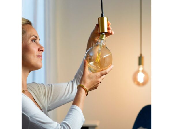 žena instaluje žárovku do svítidla bez stínítka