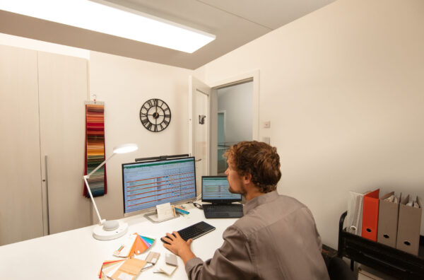 Svítidla SUN@Home v domácí kanceláři a muž pracující u počítače