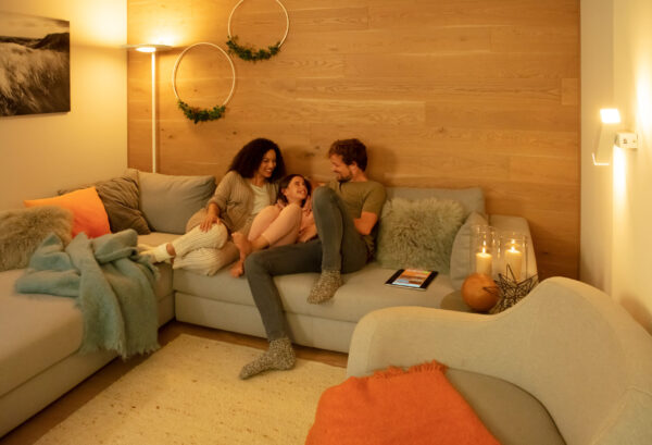 Rodina sedí na gauči v obývacím pokoji osvětleném teplým odstínem bílé