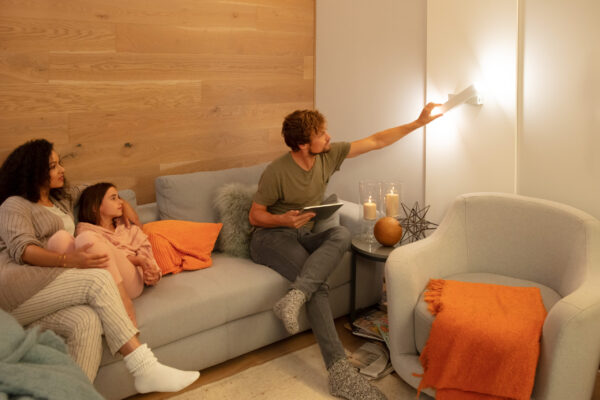 Rodina upravuje nástěnné svítidlo SUN@Home v obývacím pokoji