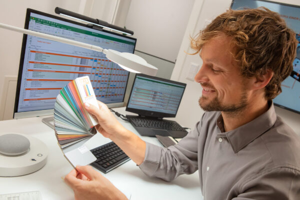 Muž prohlížející si vzorník barev pod stolní lampou PANAN DESK